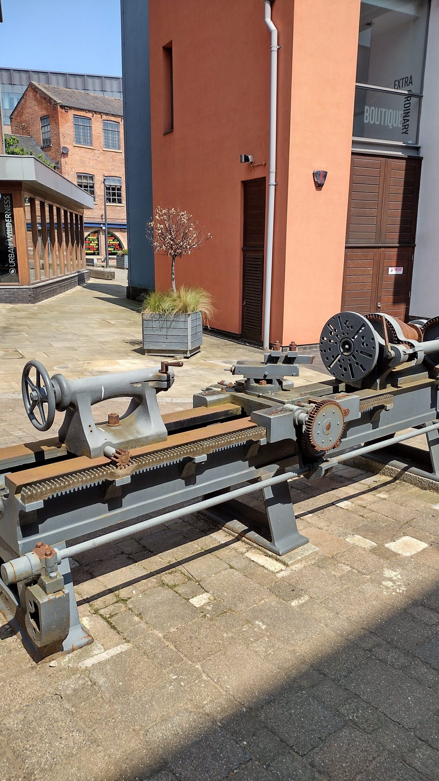 A wood or metal turning lathe on public display in a yard near Marshall's Mill