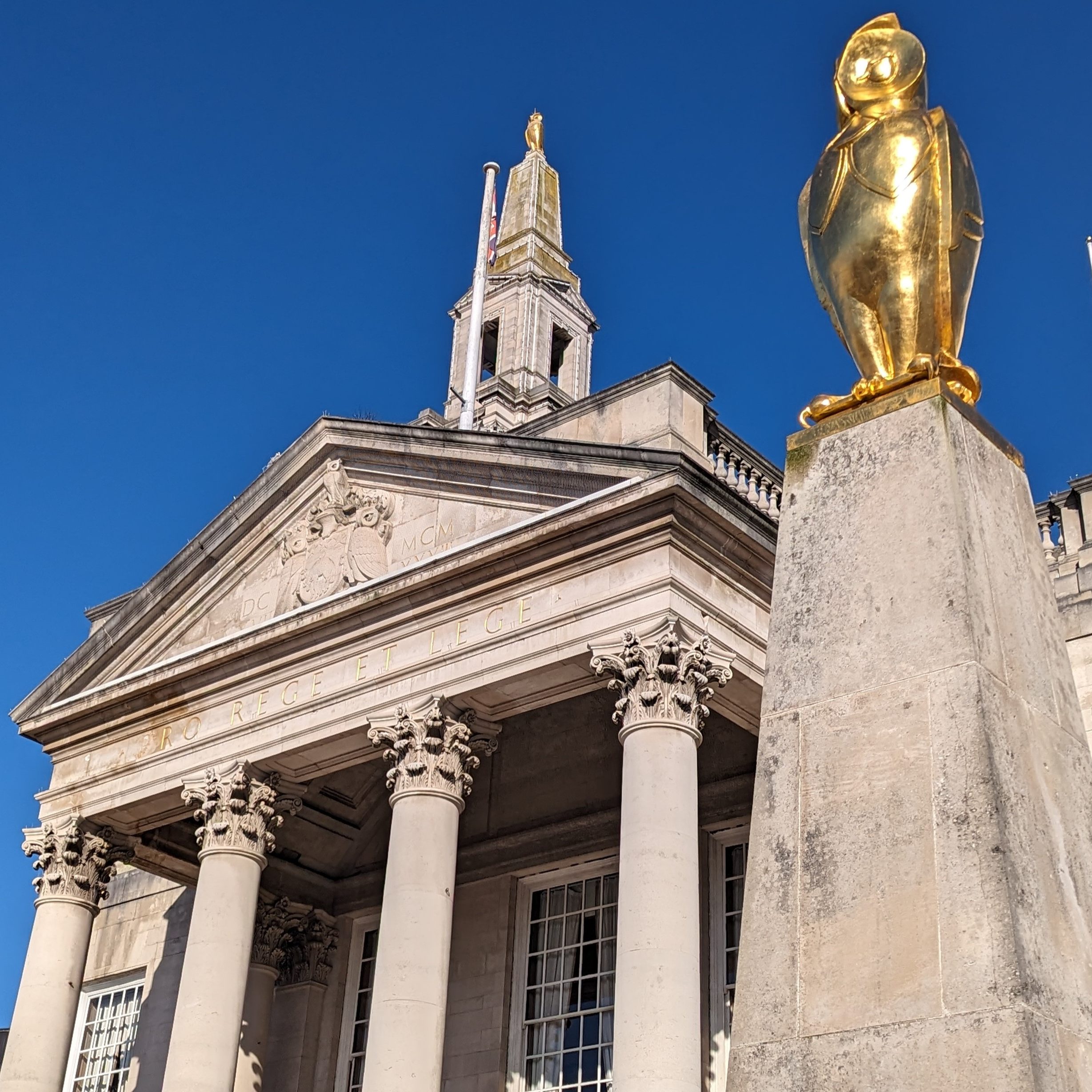 Leeds Civic Hall with a gold owl sculpture in the foreground against a backdrop of blue sky
