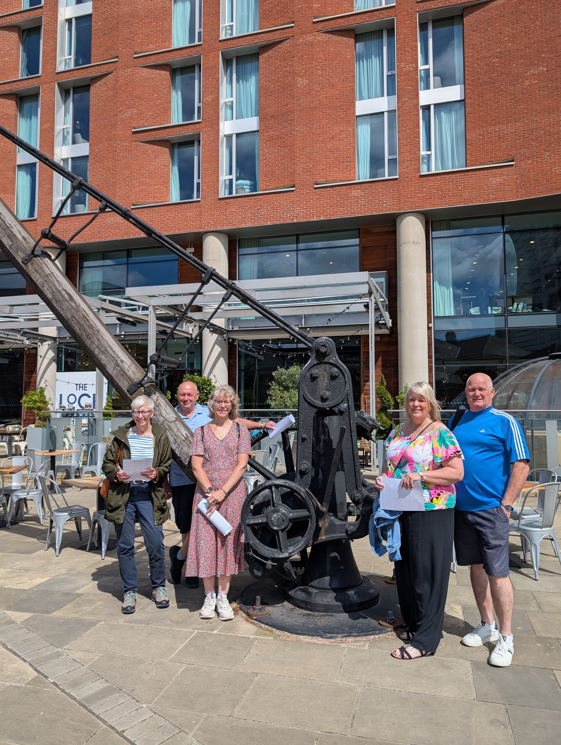 Group of people stood by a heritage lifting crane at Leeds Granary Wharf